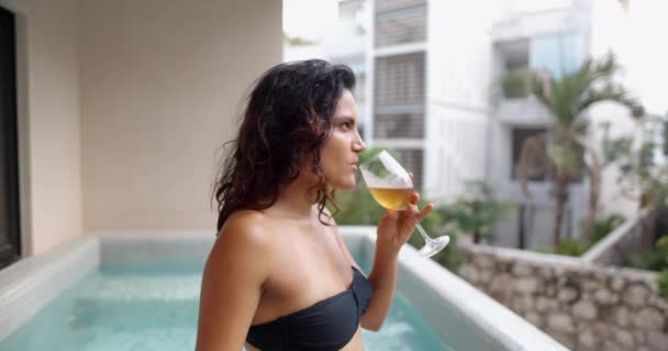 Piękna brunetka pije kieliszek szampana w basenie — Wideo stockowe