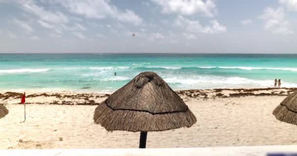 Vacker utsikt över palmparaplyer på stranden med vågigt hav som bakgrund — Stockvideo