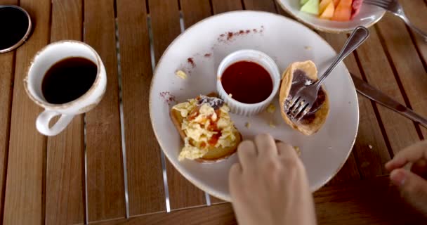 Mãos femininas colocando lentamente ovos mexidos na torrada acima da mesa de madeira — Vídeo de Stock