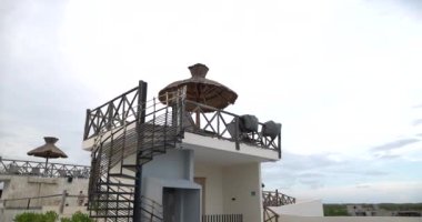 Palmiye şemsiyesi ve güneşlenmeler bulutlu gökyüzünün altında otel terasında