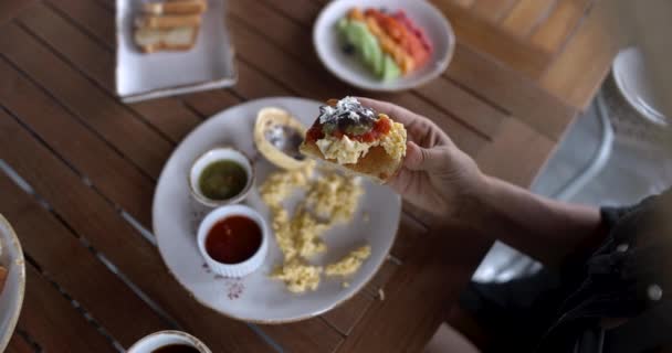 달걀 스크램블, 핫소스, 튀긴 콩 과 함께 토스트를 들고 있는 암컷 손 — 비디오