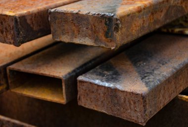 Bir yığın metal dikdörtgen profil, bir inşaat malzemeleri mağazasının sahasında dikdörtgen çapraz metal borular, metal yapı malzemeleri.