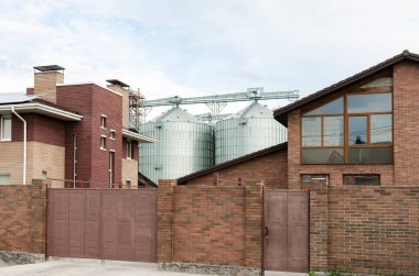 Granary elevator for export wheat near town houses. Silos agro plant for processing drying cleaning, storage of agricultural products grain. Large iron terminal of grain