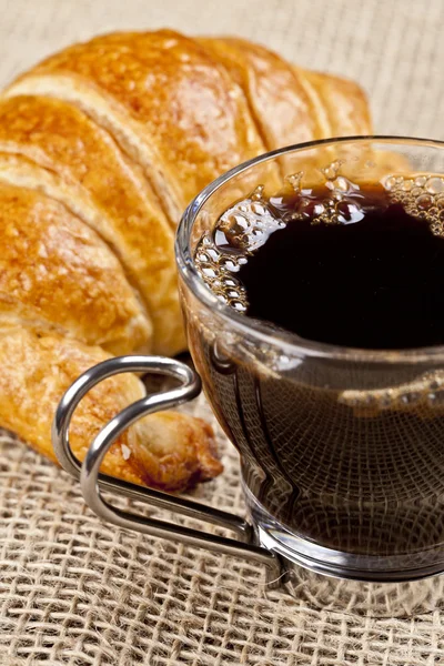 Uma xícara de café com um croissant — Fotografia de Stock