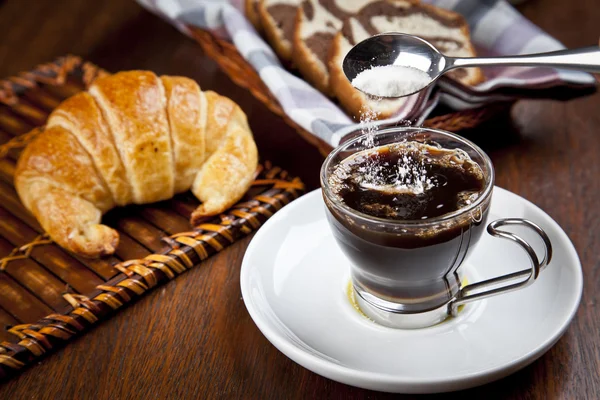 Uma xícara de café com croissant e uma cesta de bolo — Fotografia de Stock