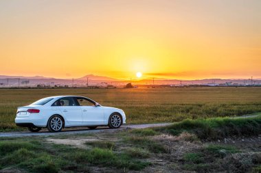 Car at sunset between the rice fields of the Albufera de Valencia natural park, Spain.
