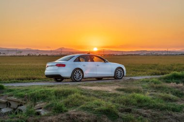 Car at sunset between the rice fields of the Albufera de Valencia natural park, Spain.