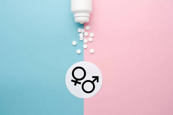 Pills scattered from a jar on a blue and pink background. Symbol of male and female. The concept of reproductive health and hormone therapy. Top view, background, space for text, copy space — Stock Photo, Image