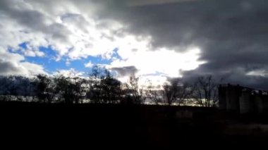 Hareket halindeki bir trenden görüntü. Gökyüzü, bulutlar, ağaçlar.