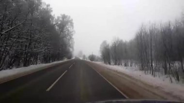 Kış yolu. Kar yağıyor. Asfalt. Ağaçlar. Öndeki arabadan bak..