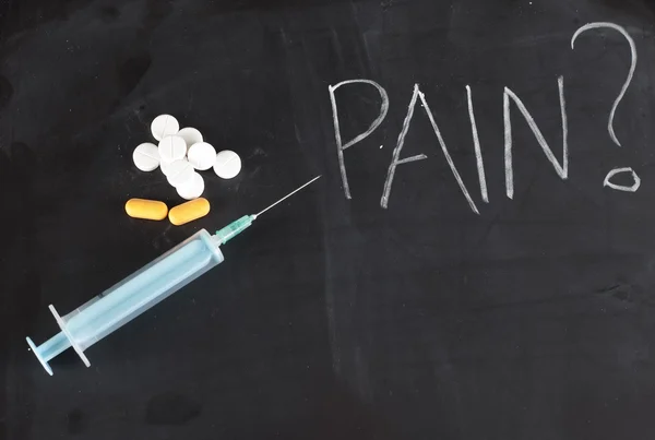 Syringe and pills on chalkboard with pain — Stock Photo, Image