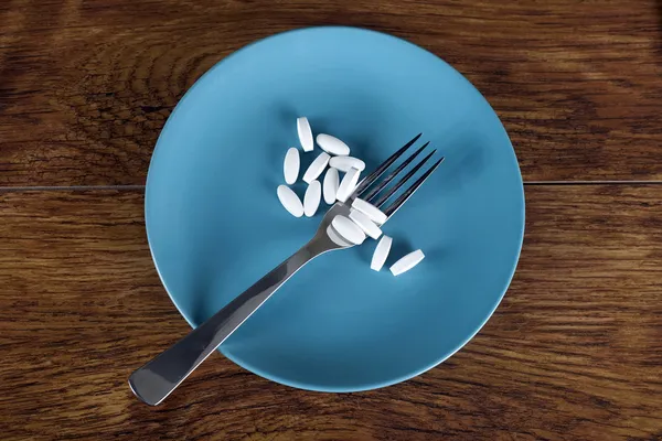 Concepto de pérdida de peso píldoras de dieta en plato con tenedor —  Fotos de Stock