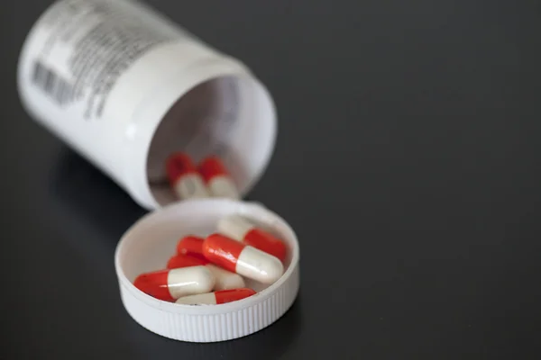 White and orange capsules with bottle — Stock Photo, Image