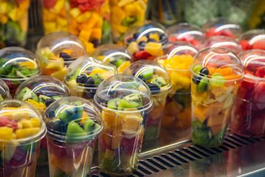 Bir fincanda meyve dilimleme. Dükkanda içinde taze meyve parçaları olan plastik bir kutu sergisi. Uygun, sağlıklı. 