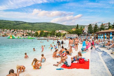 Selce. Hırvatistan 20 Temmuz 2021. Kumlu plajda insanlar var. Denizde bir tatilin başlangıcı. 