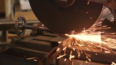 Çalışan adam makinedeki metal boruları kesiyor. Metalle çalışmak. Demirci. yakın plan.