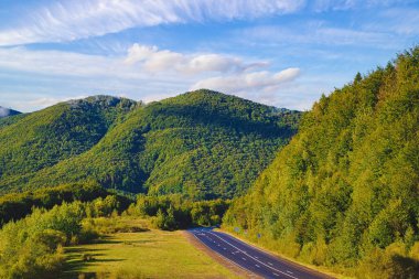  Dağın tepeleri boyunca uzanan dağ ve köy manzaralı dağ yolu. Dağların arka planında bile ağaçlar ve açıklıklar var. seyahat kavramı. 