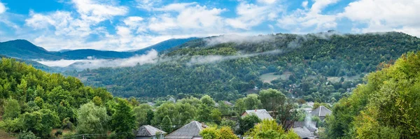 countryside on the background of mountains in the morning fog panorama. majestic view of beautiful misty mountains in misty landscape. Dramatic unusual scene. Travel background. Exploring the world of beauty. Carpathians. Ukraine. Europe.