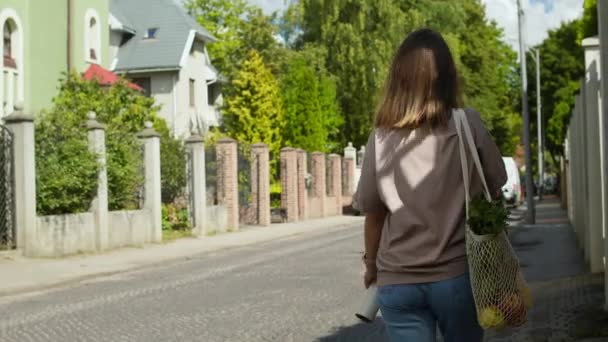 Vrouw wandelingen met mesh string gebreide boodschappentas — Stockvideo