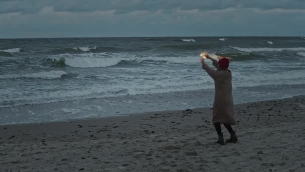 Žena slaví na pobřeží oceánu s ohňostrojem jiskry — Stock video