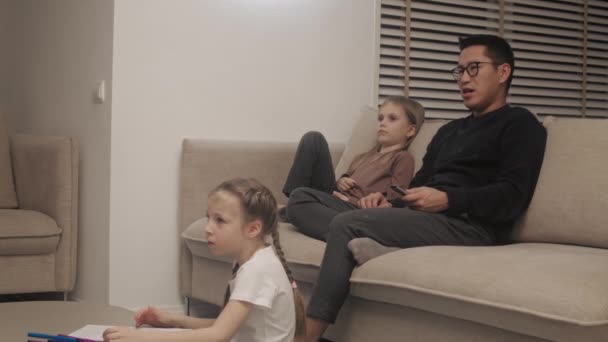 Father watching TV with daughters — Stockvideo