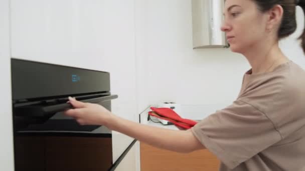 Mujer abre el horno para comprobar las galletas — Vídeo de stock