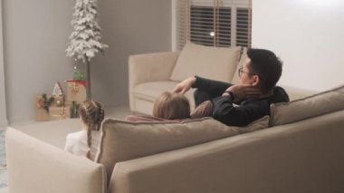 Adam çocuklarla televizyon izliyor.