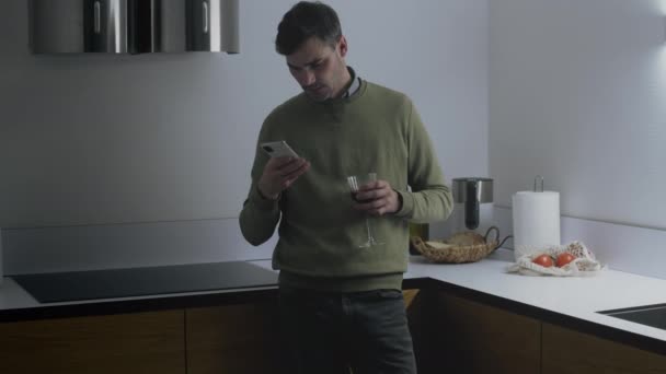 Чоловік розслабляється на кухні зі склом вина — стокове відео