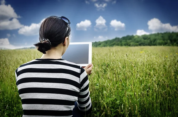 Девушка с планшетом в парке на траве . — стоковое фото