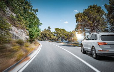 Araba yol boyunca gidiyor. Banliyö yolunda beyaz bir araba..