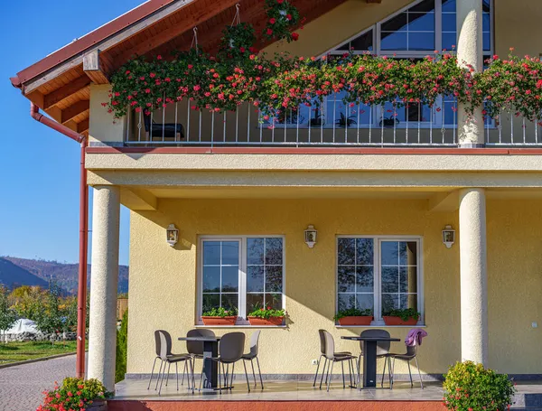 Ein Teil des Hauses mit einer schönen Terrasse und einem Balkon mit Blumen. — Stockfoto