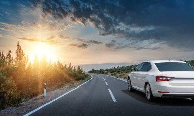 Araba yol boyunca gidiyor. Banliyö yolunda beyaz bir araba..