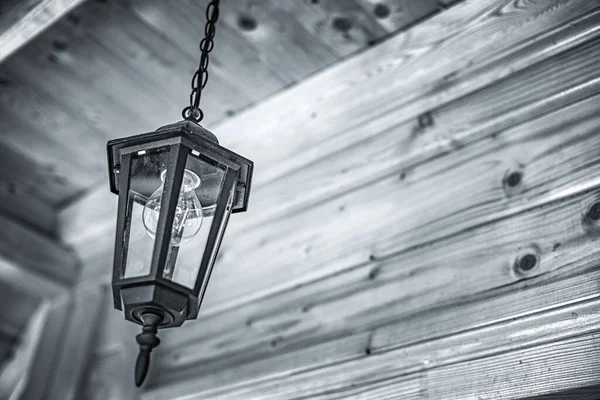 Old lantern against the background of a wooden ceiling. — Stock Photo, Image