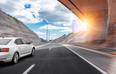 Araba yol boyunca gidiyor. Banliyö yolunda beyaz bir araba..