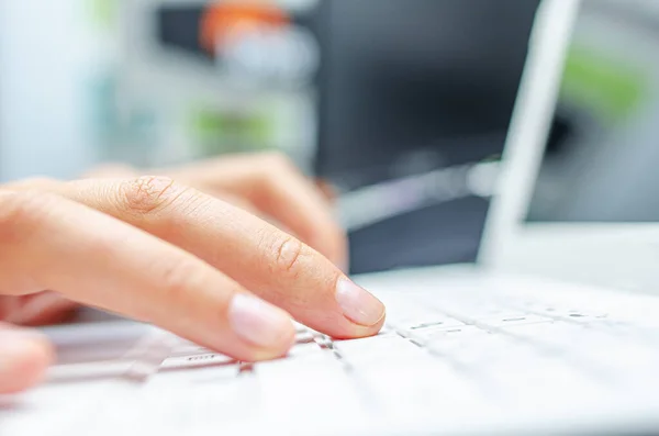 Una donna sta digitando su una tastiera bianca per laptop. — Foto Stock