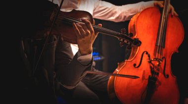Müzisyenler konserde keman ve çello çalarlar.