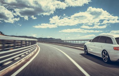 Araba yol boyunca gidiyor. Banliyö yolunda beyaz bir araba..