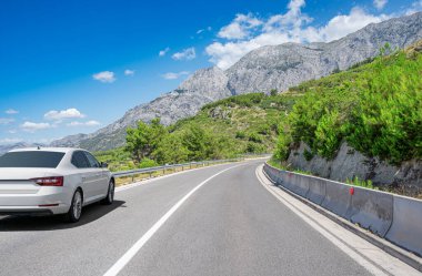 Güzel bir yol boyunca beyaz bir araba sürüyor..