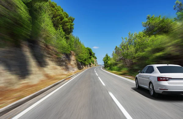 Güzel bir yol boyunca beyaz bir araba sürüyor..