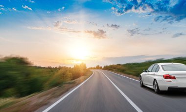 A white car drives along a beautiful road.