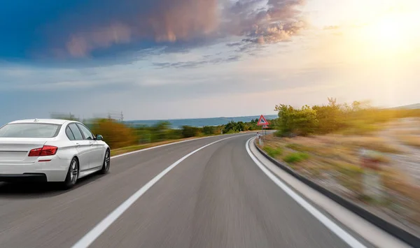 Um carro branco dirige ao longo de uma bela estrada. — Fotografia de Stock