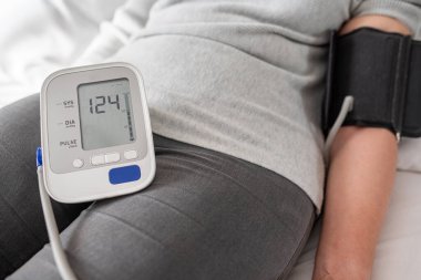 Tansiyon. Bir kadın yatakta yatarken tansiyonunu ölçüyor..