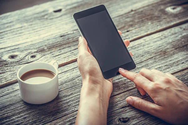 Smartphone Handen Achtergrond Van Een Houten Tafel Een Kopje Koffie — Stockfoto