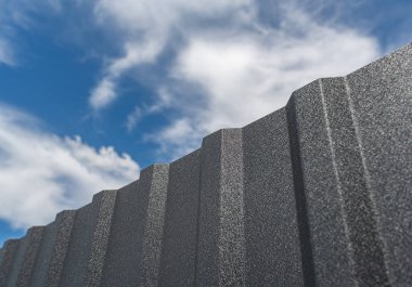 Demir çit ve mavi gökyüzü. Profilli bir çarşaftan beyaz bulutlu bir çit..