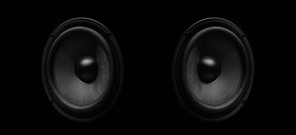 Pair of black speakers close-up on a dark background.