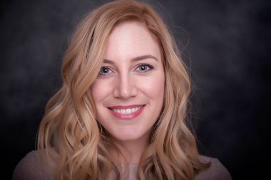 Koyu arkaplanda gülümseyen güzel sarışın..