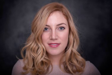 Koyu arkaplanda gülümseyen güzel sarışın..