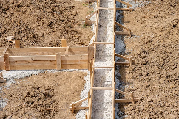 Wooden formwork for pouring concrete foundation of the house. Foundation construction.