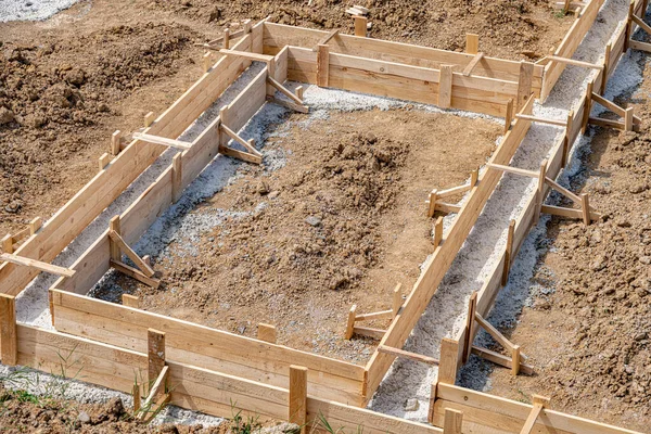 Wooden formwork for pouring concrete foundation of the house. Foundation construction.