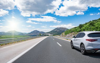 Güneşli bir yaz gününde güzel bir yolda beyaz bir araba sürüyor..
